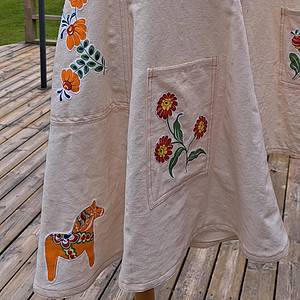 Handgjord sommarklänning med traditionella blomsterbroderier, unik design och naturmaterial, perfekt för bohemiska och etniska stilar.