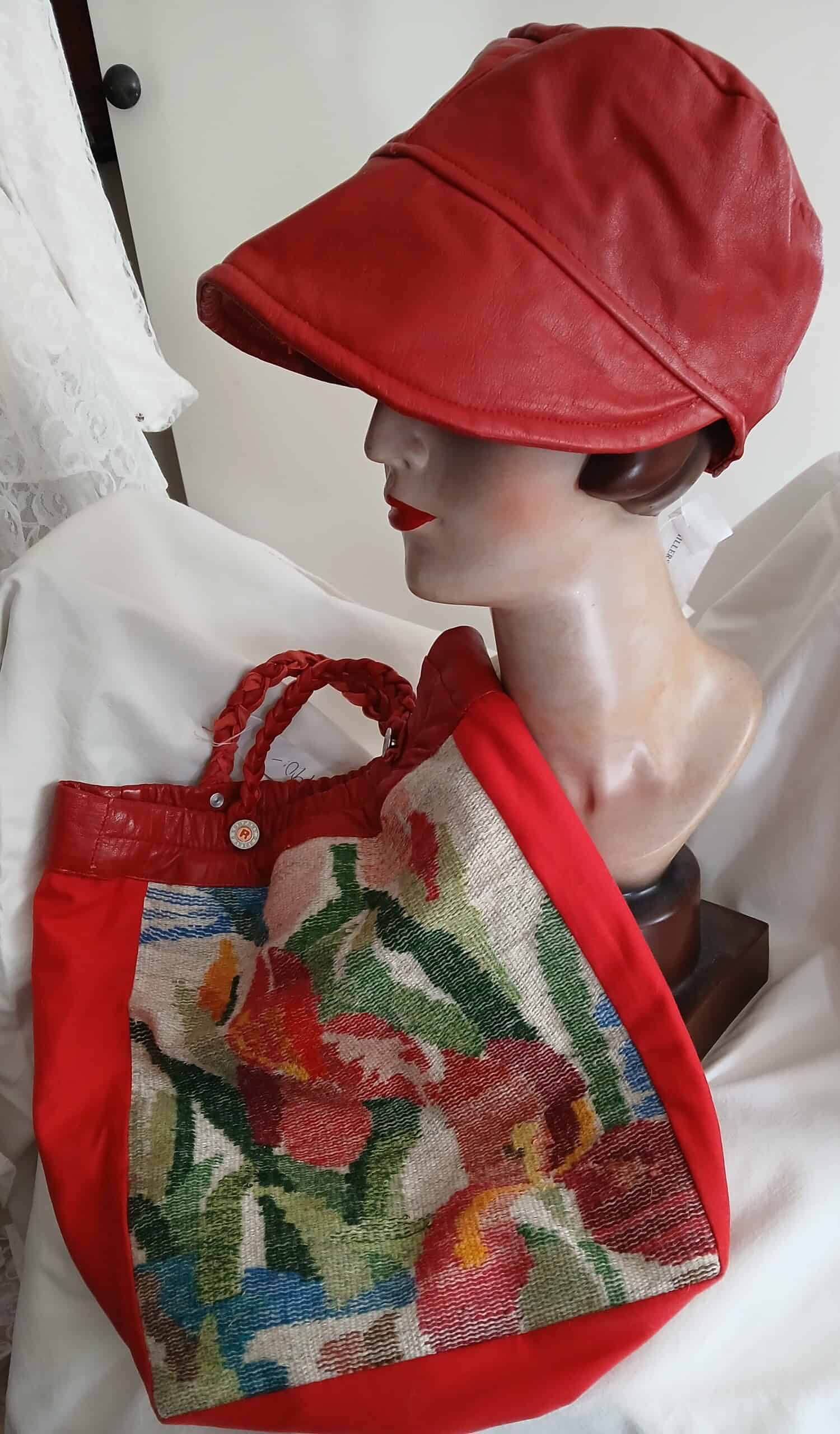 Röd lädermössa och handväska med broderat blommönster på ett mannequin. Perfekt för personlig branding och skyltning med hög synlighet. Designad för att skapa ett modernt och professionellt intryck.