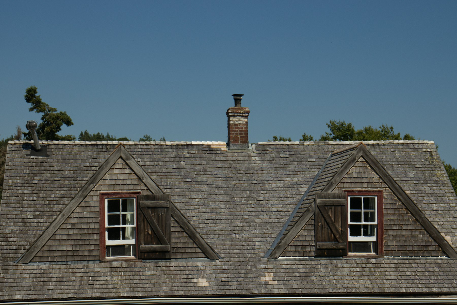 Dormer windows on a shingled roof of a Cape Cod home, the kind of roof a Sandwich MA roofing contractor works on