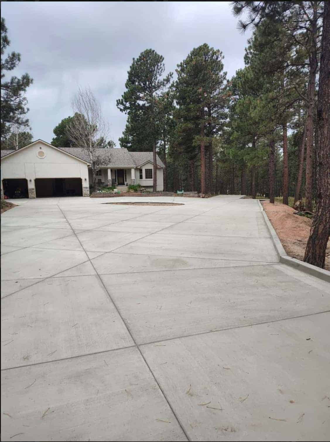 Expansive new concrete driveway and turnaround at forested Colorado Springs acreage home.