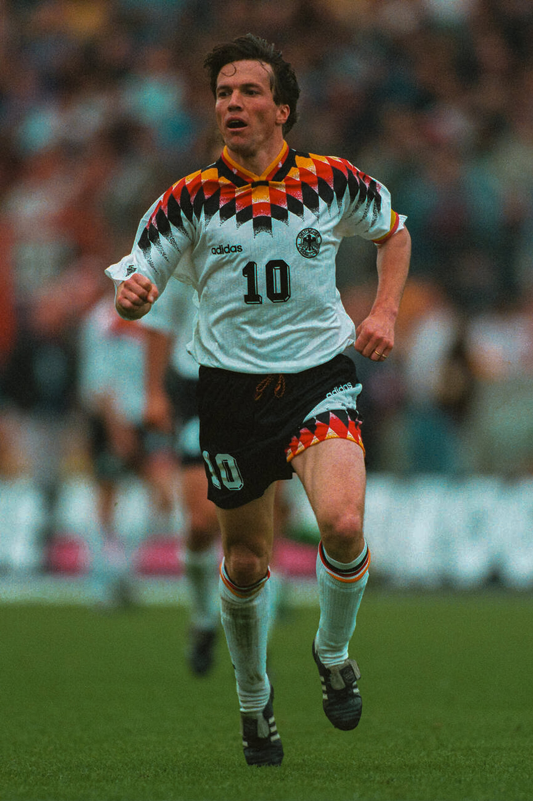 Jugador de fútbol con uniforme de Alemania en movimiento en el campo.