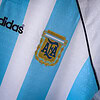 Camisa de fútbol de Argentina con logotipo y rayas azules y blancas, diseñada para fans y jugadores.