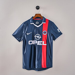 Camisa de fútbol del PSG en color azul con franjas rojas, logo de Opel y diseño de alta calidad.