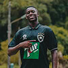 Camisa de fútbol con logo y patrocinador, deportista sonriendo en campo abierto, estilo deportivo y moda deportiva.