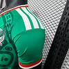 Camiseta de fútbol verde con detalles en blanco y rojo, vista cercana, estilo deportivo.