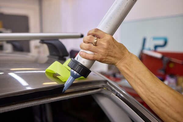 Technician calibrating car windshield with precision tool.
