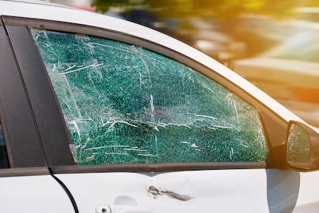 Broken car window with cracks and damage for auto glass repair.