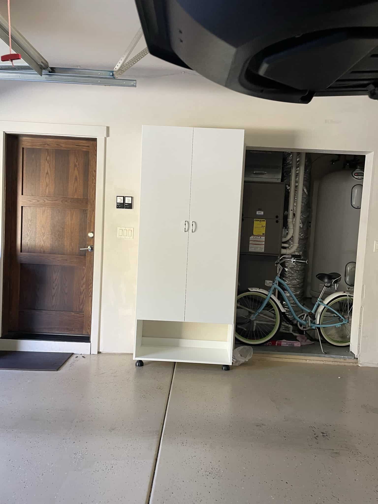Custom garage storage cabinet with utility area and bicycle in Durango home.