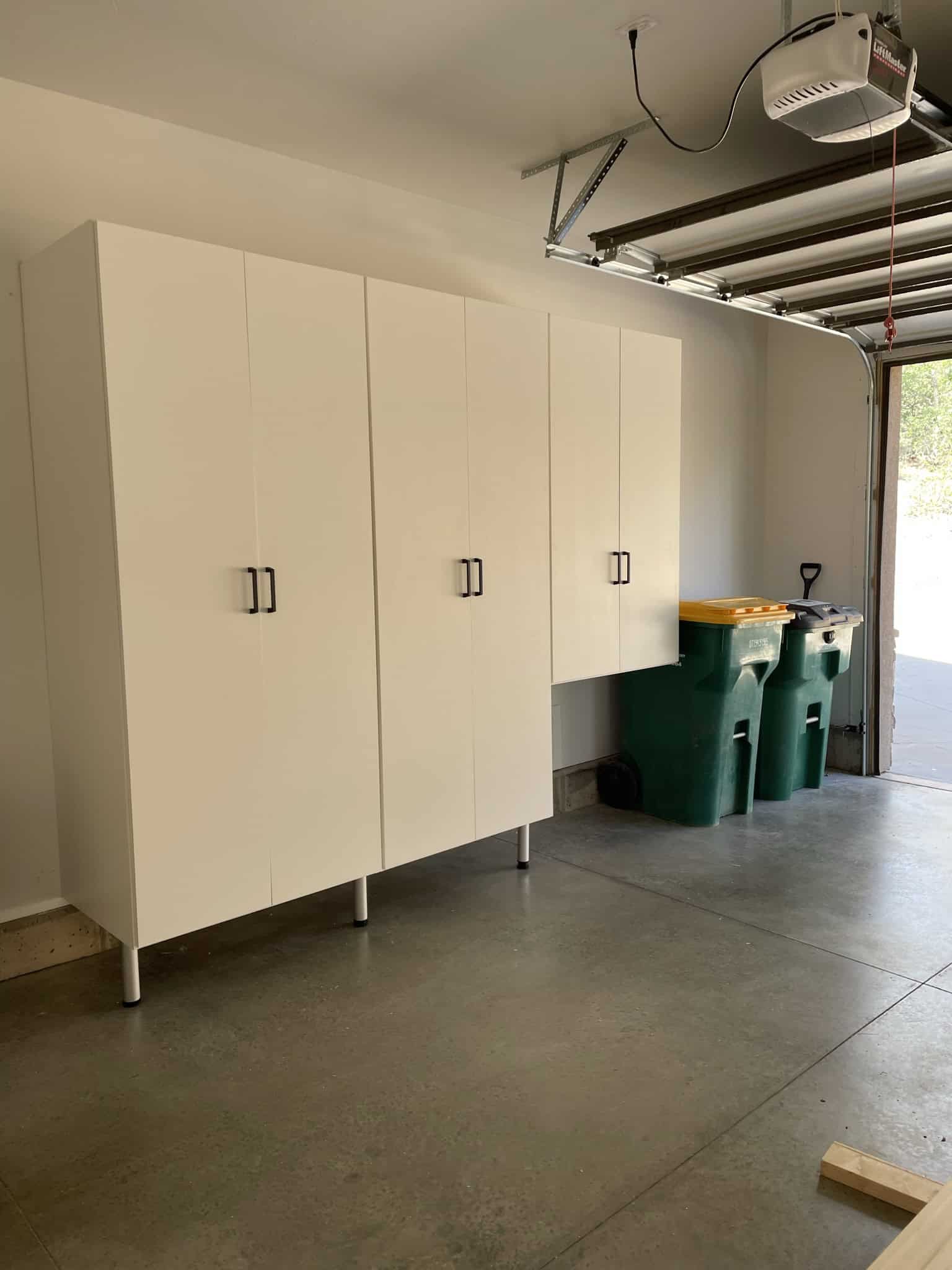 White custom garage cabinets with sleek handles in a spacious garage.