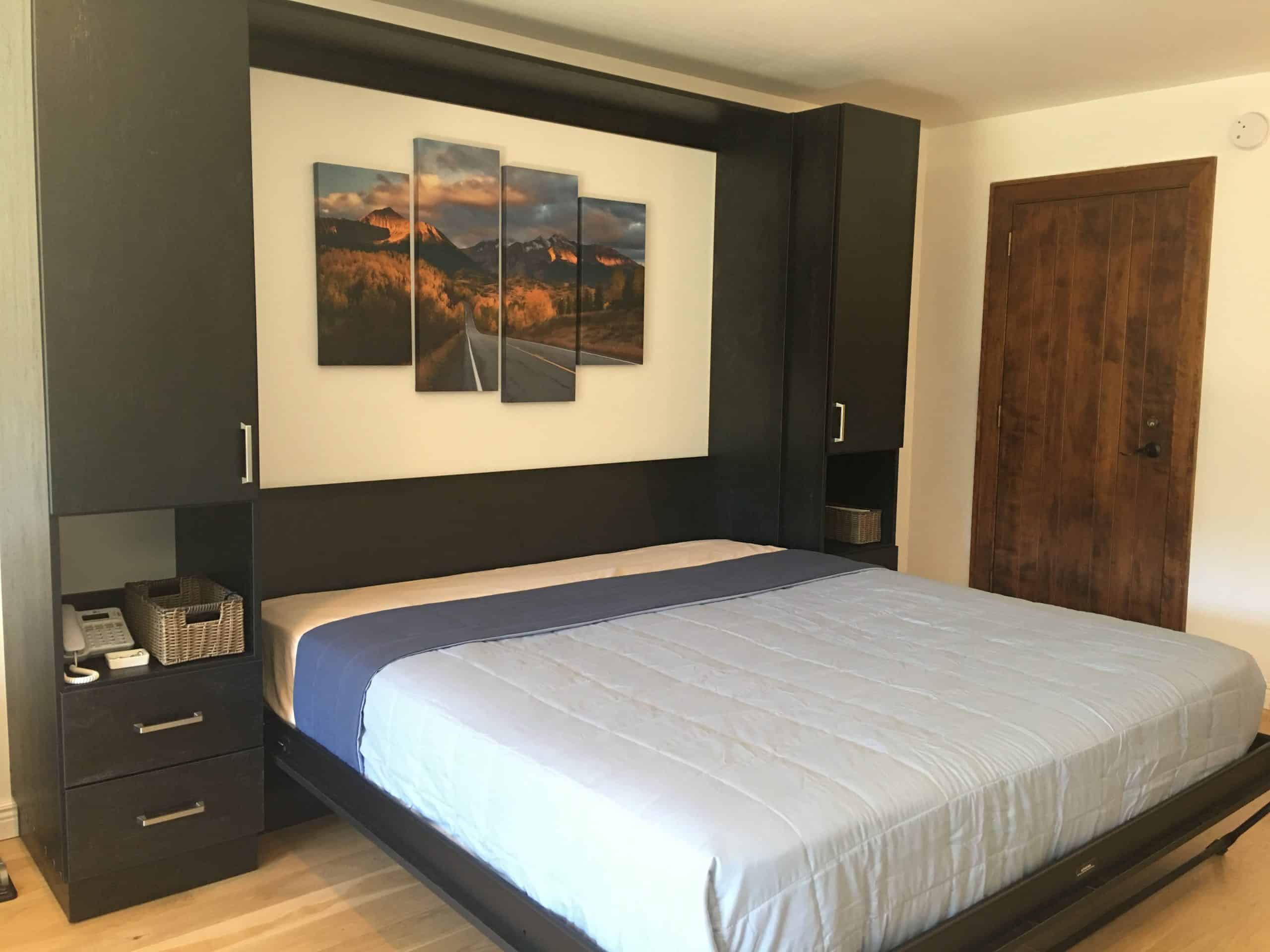 Modern bedroom with custom black closet and mountain artwork above bed.