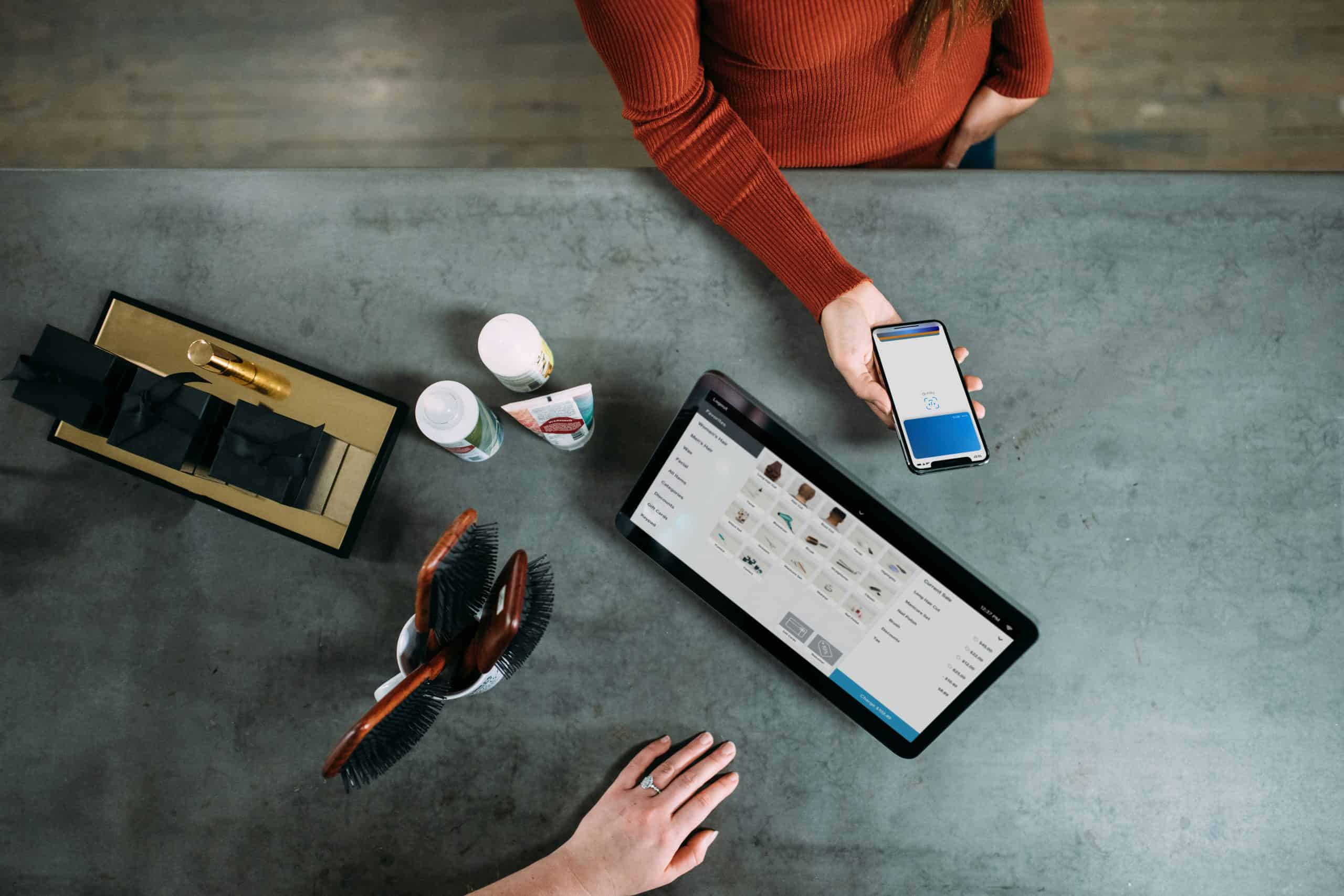 Person using tablet and smartphone at a modern workspace with office supplies.