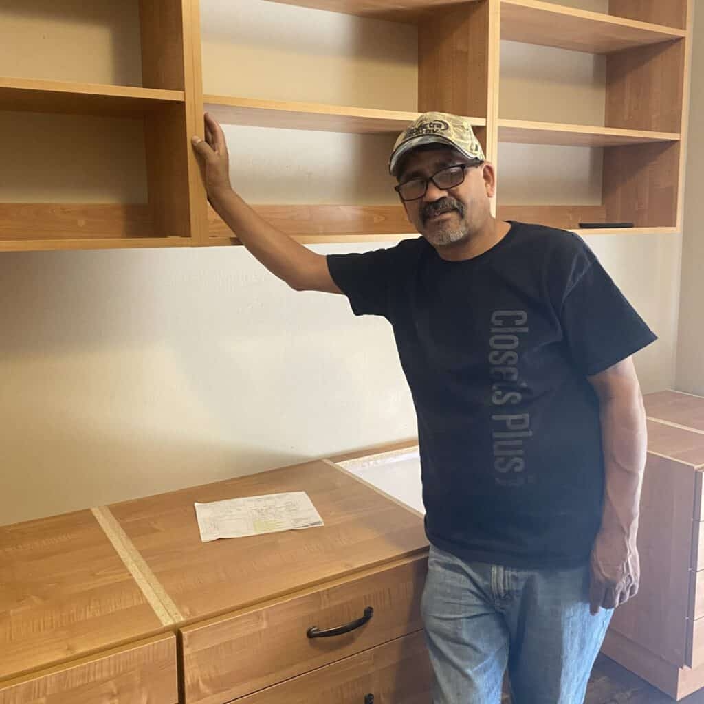 Man inspecting custom wooden closet shelves in a home.