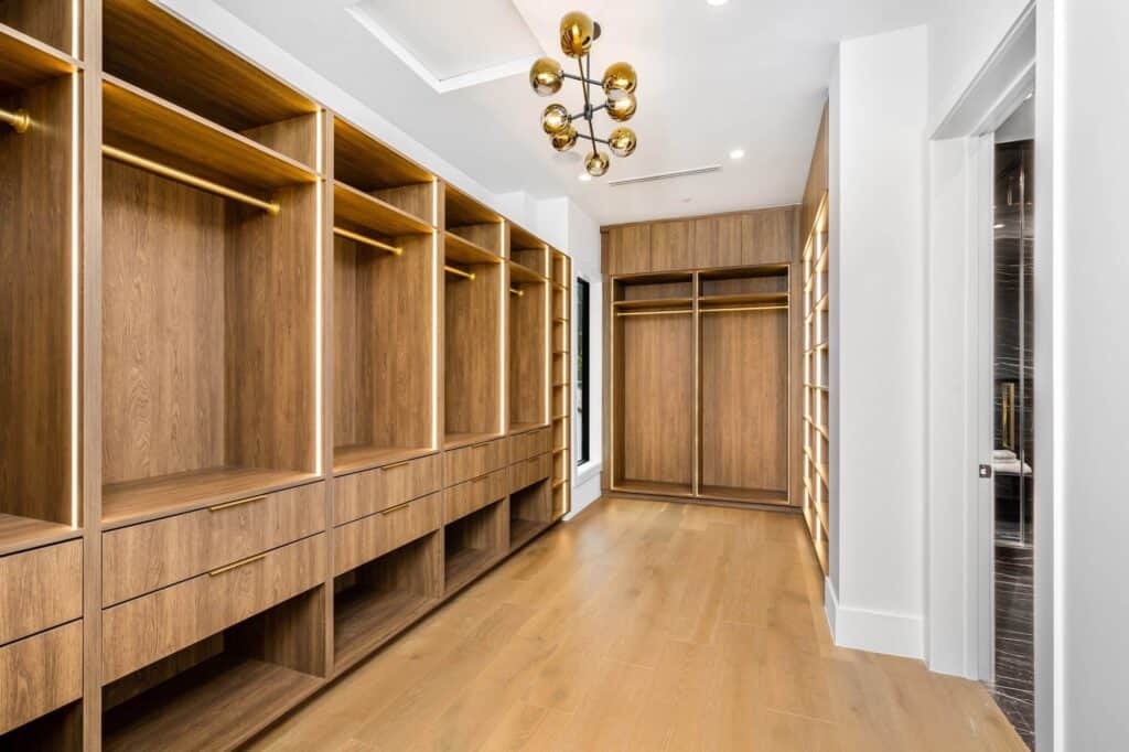Modern custom walk-in closet with wooden cabinetry and ample storage space.