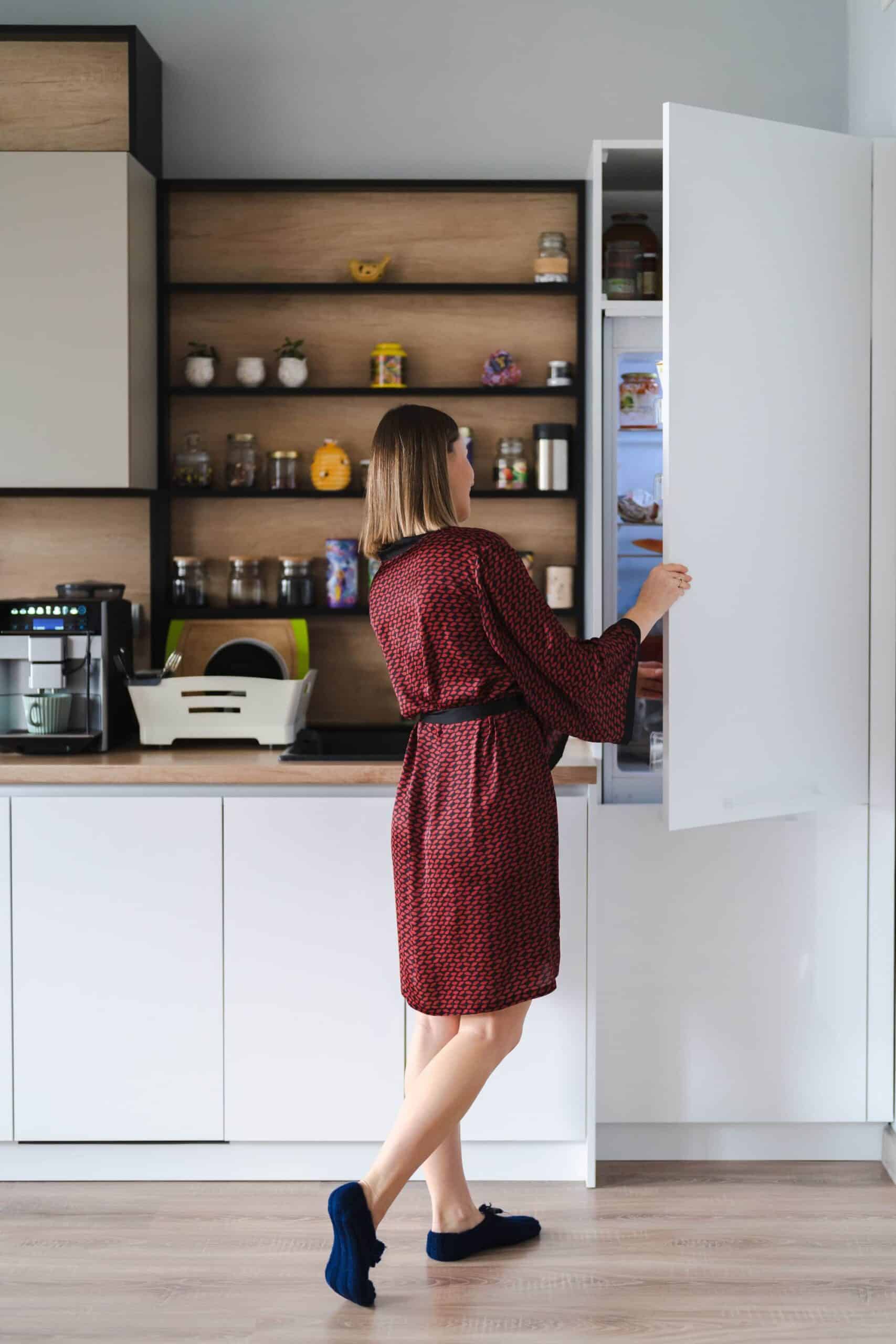 Woman accessing organized pantry in modern kitchen.