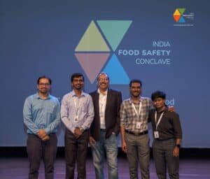 Group of professionals at India Food Safety Conclave posing for a photo on stage.
