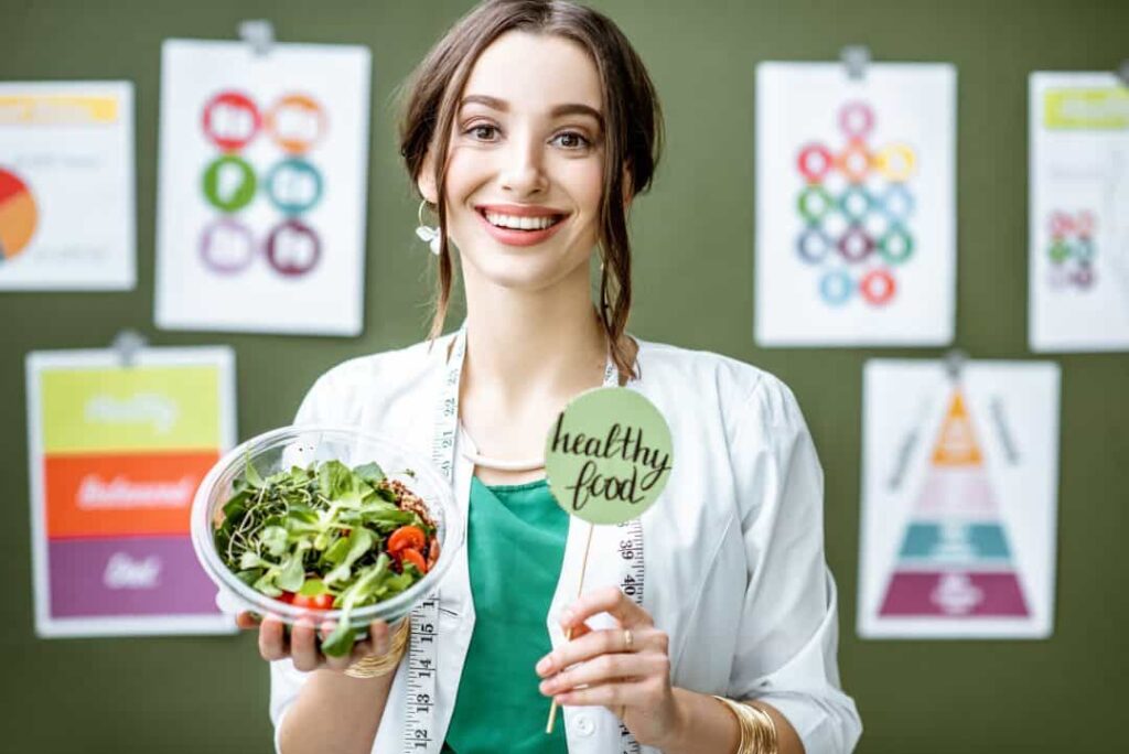 Healthy food advocate holding a salad with a "healthy food" sign at India Food Safety Conclave.