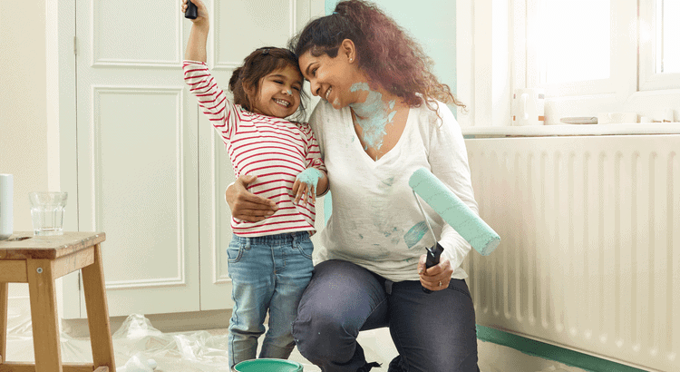A joyful mother and daughter painting walls together in a cozy home.