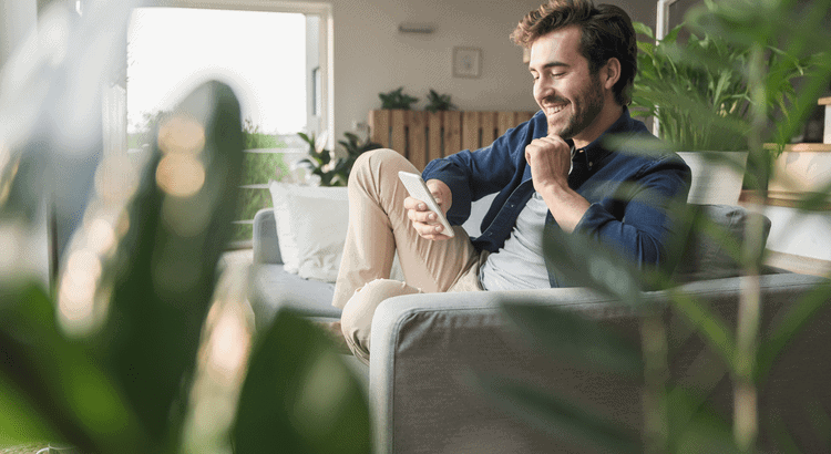 Happy man using smartphone at home in Walnut Creek, CA.