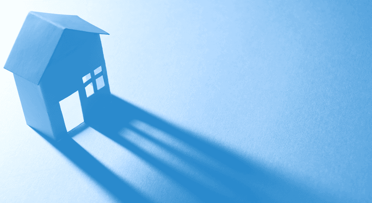 Blue paper house with shadow representing real estate and home ownership.