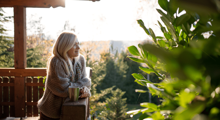 Walnut Creek realtor woman enjoying morning on balcony with coffee and nature view.