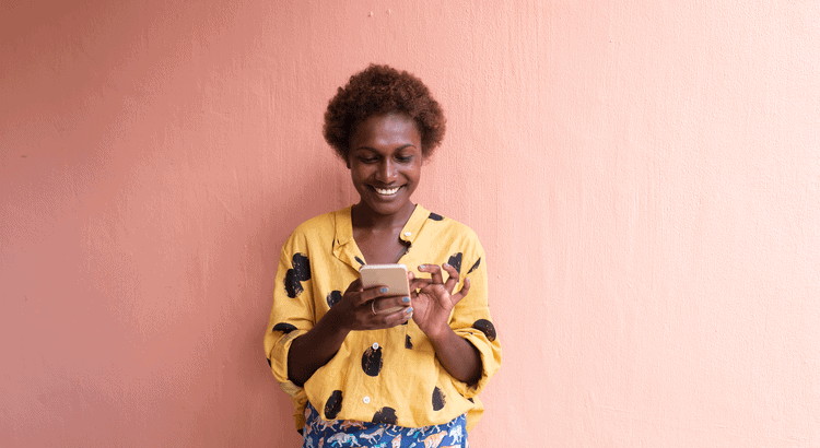 Walnut creek real estate agent smiling with smartphone against pink wall.