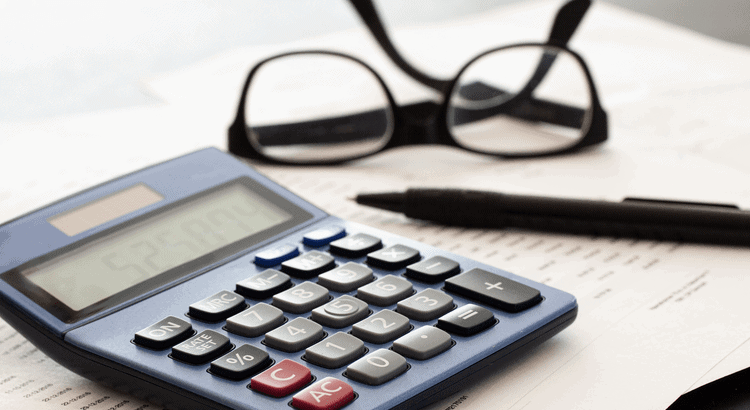 Calculator with papers and glasses on desk in Walnut Creek, CA real estate office.
