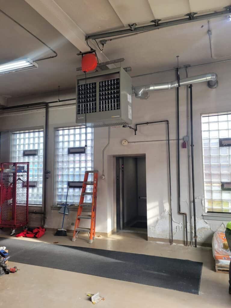 JP Heating & Cooling installs an HVAC unit in a utility room, showing a work area with tools and equipment.