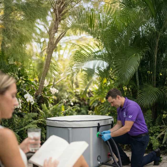 Cool Bionic technician attaching a hose to a covered Vitalis 3 tub in a garden, concierge service visit