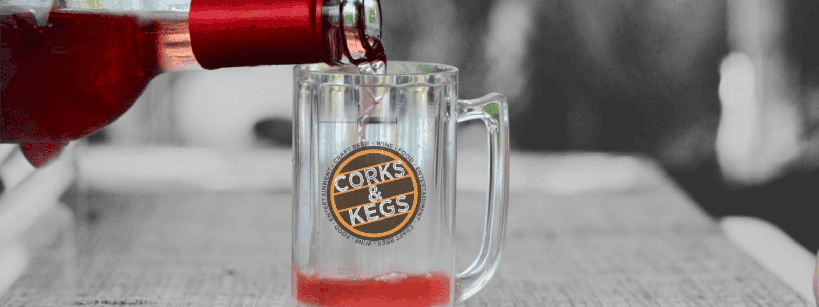 Close-up of a beer glass with Corks & Kegs logo at the festival.