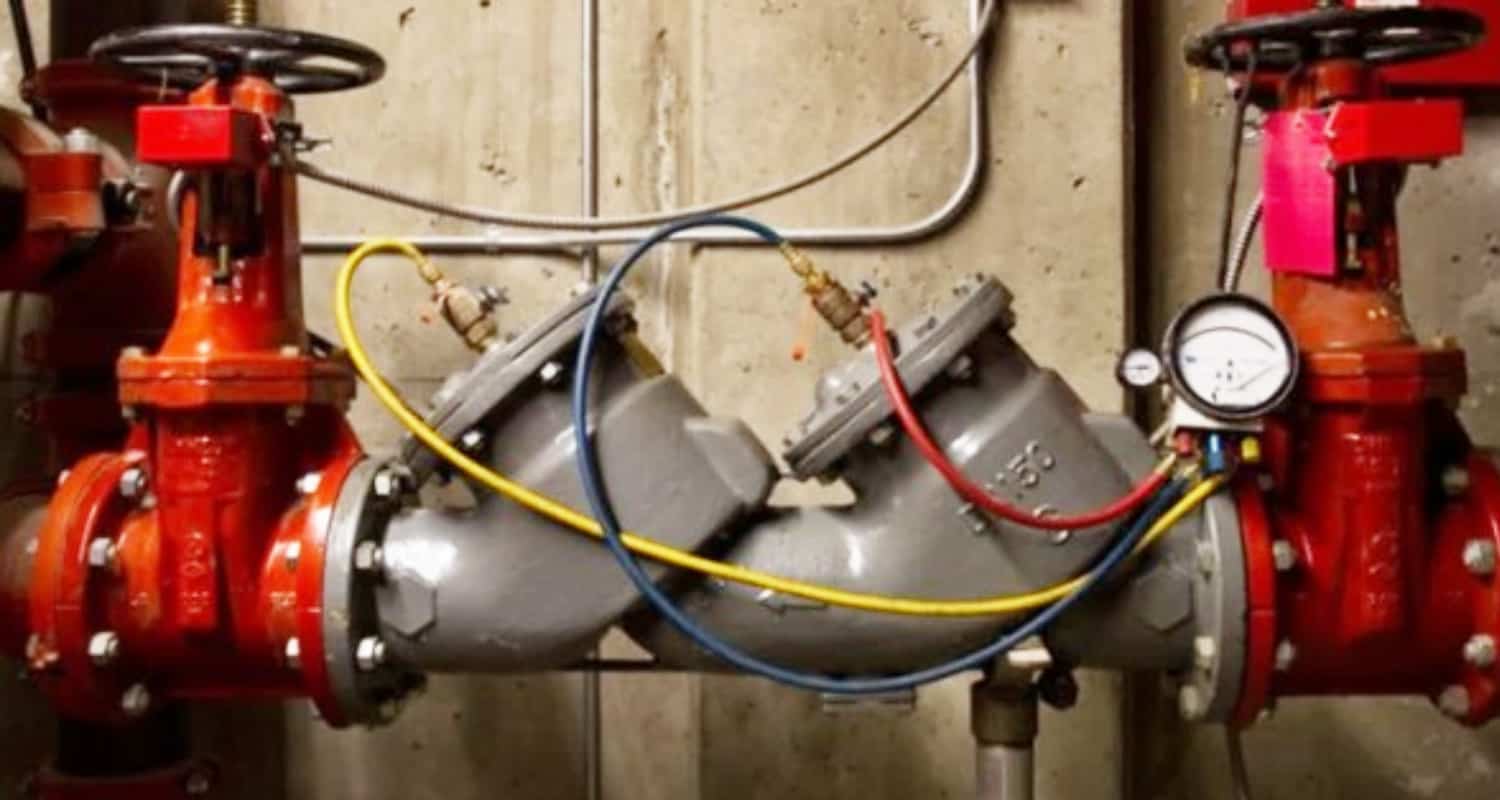 Fire protection sprinkler system valve assembly with gauges and piping in an industrial setting.