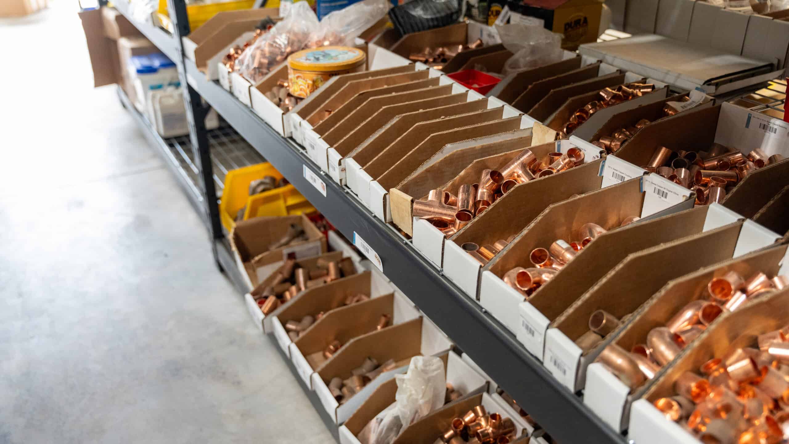 Copper plumbing fittings and pipes in organized boxes at a hardware store.