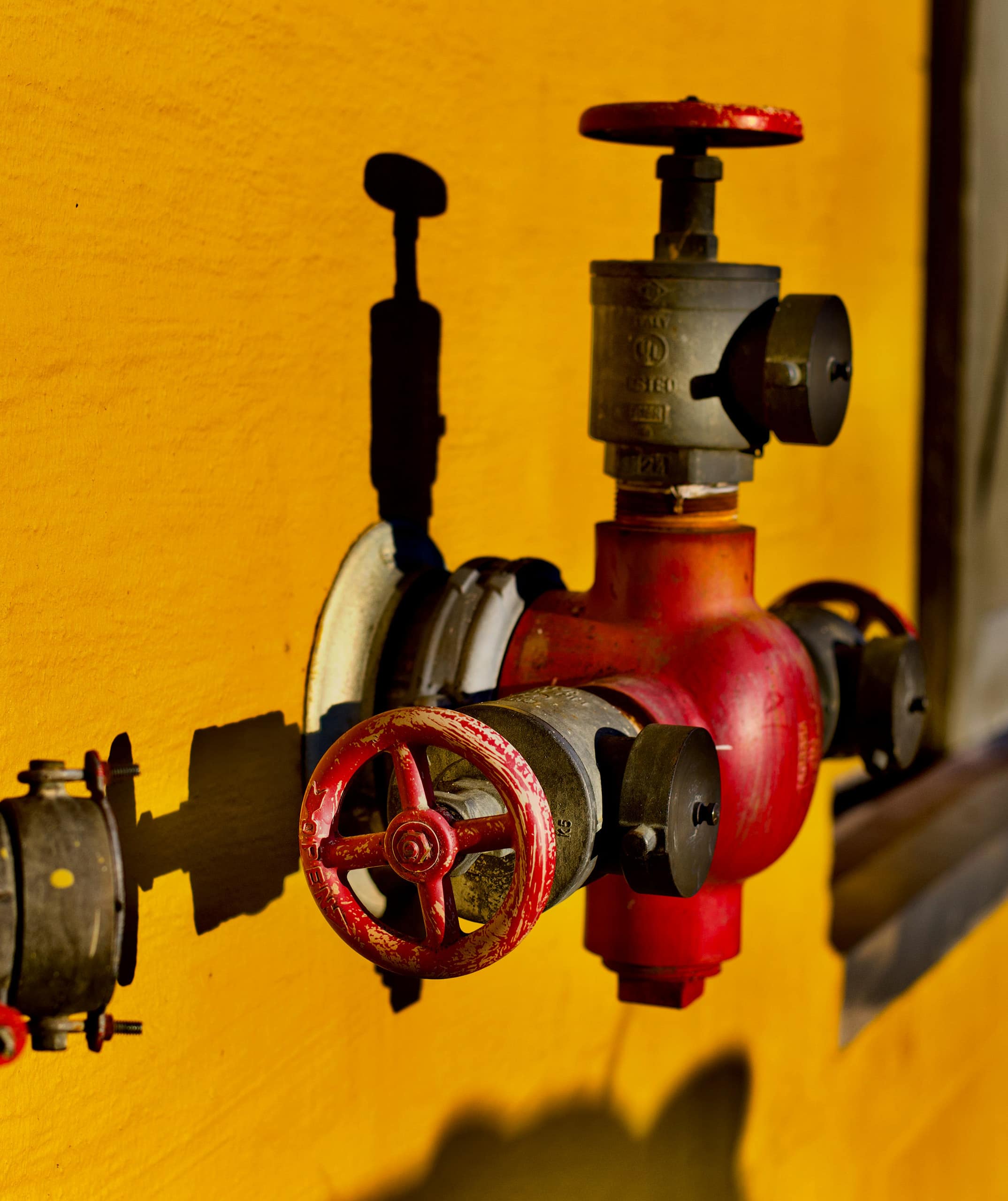 Valve assembly against a yellow background, representing plumbing system components and maintenance services offered by Cornwell Plumbing.