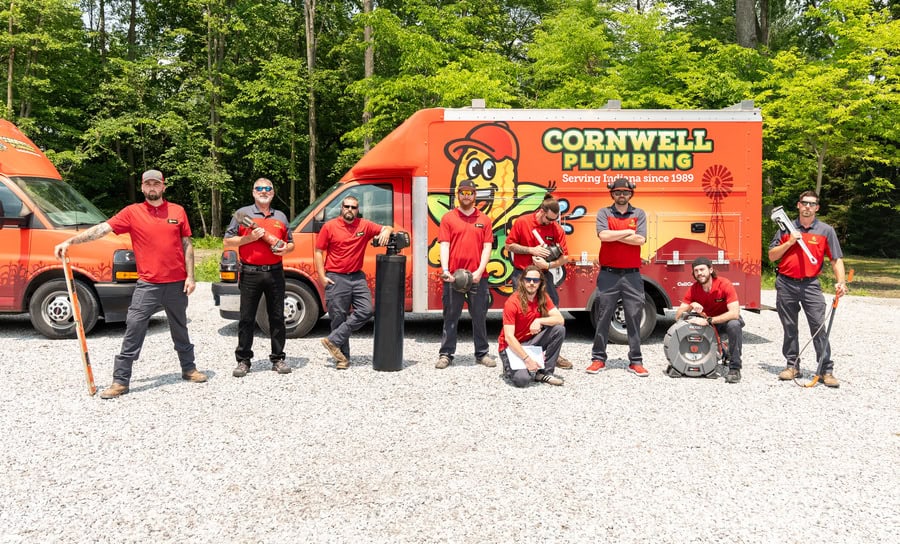Cornwell Plumbing team standing in front of branded service vehicles and equipment, ready for plumbing service in Indiana.
