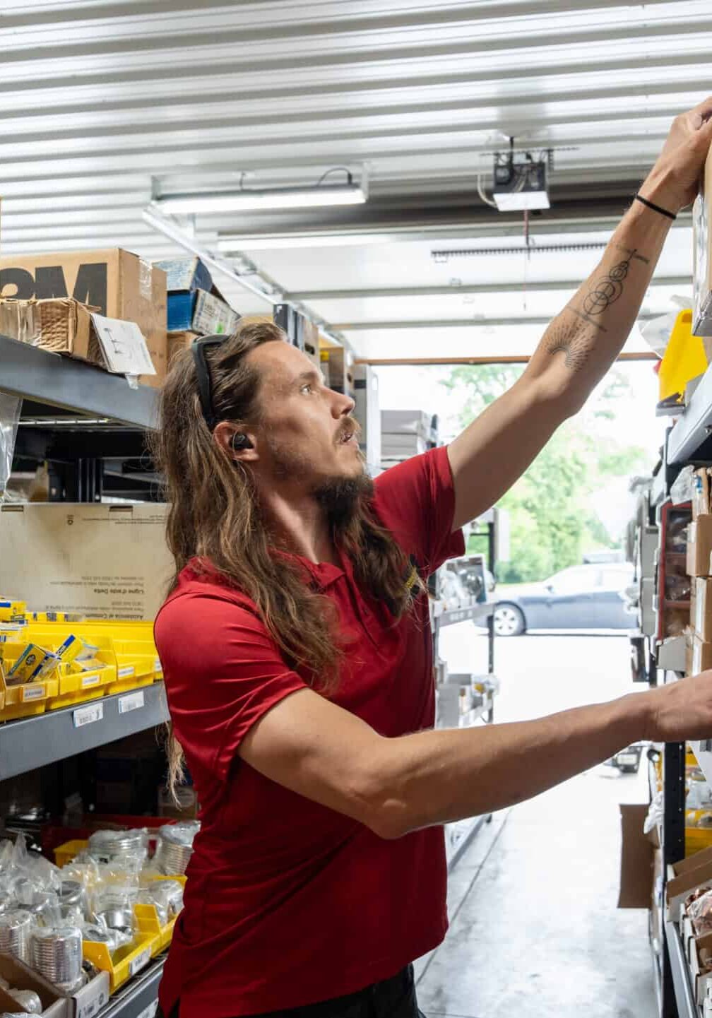 Flexible red and yellow hoses with plumbing fittings on metal shelving in a hardware store.