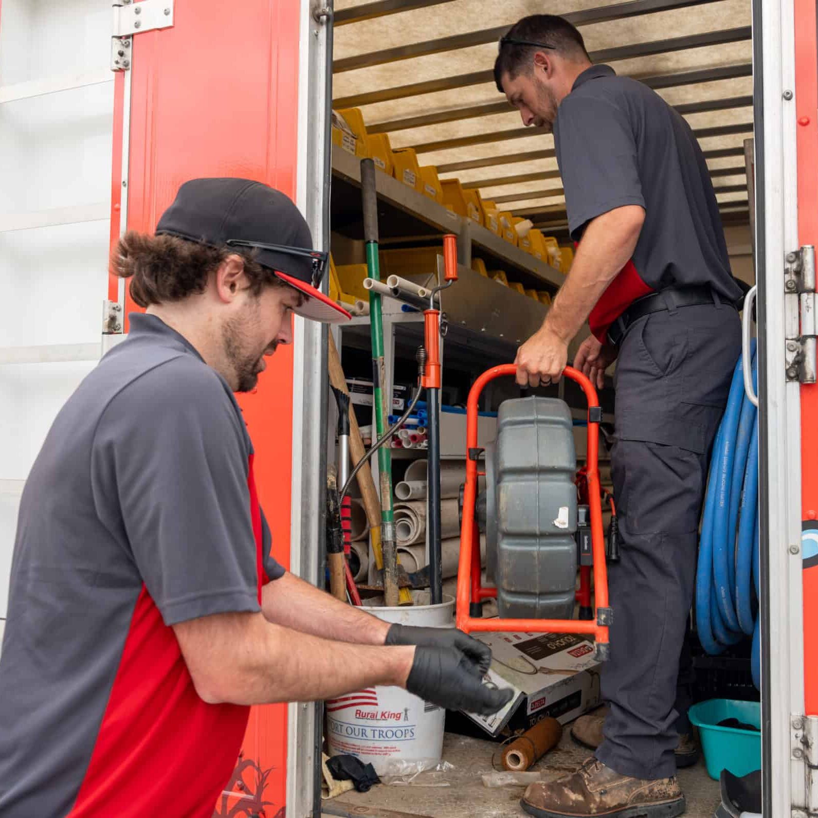 Water heater repair outdoor plumbing service truck with technicians working, plumbing tools, pipes, and equipment, professional plumbing solutions by Cornwell Plumbing.