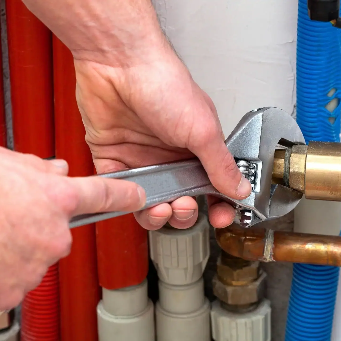 Wrench tightening copper plumbing pipe fitting for residential plumbing repair and installation services.