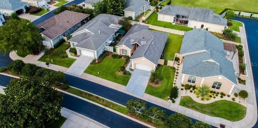 Aerial view of suburban homes with well-maintained lawns, showcasing modern houses with various roof styles and driveways, illustrating neighborhood quality and community living.