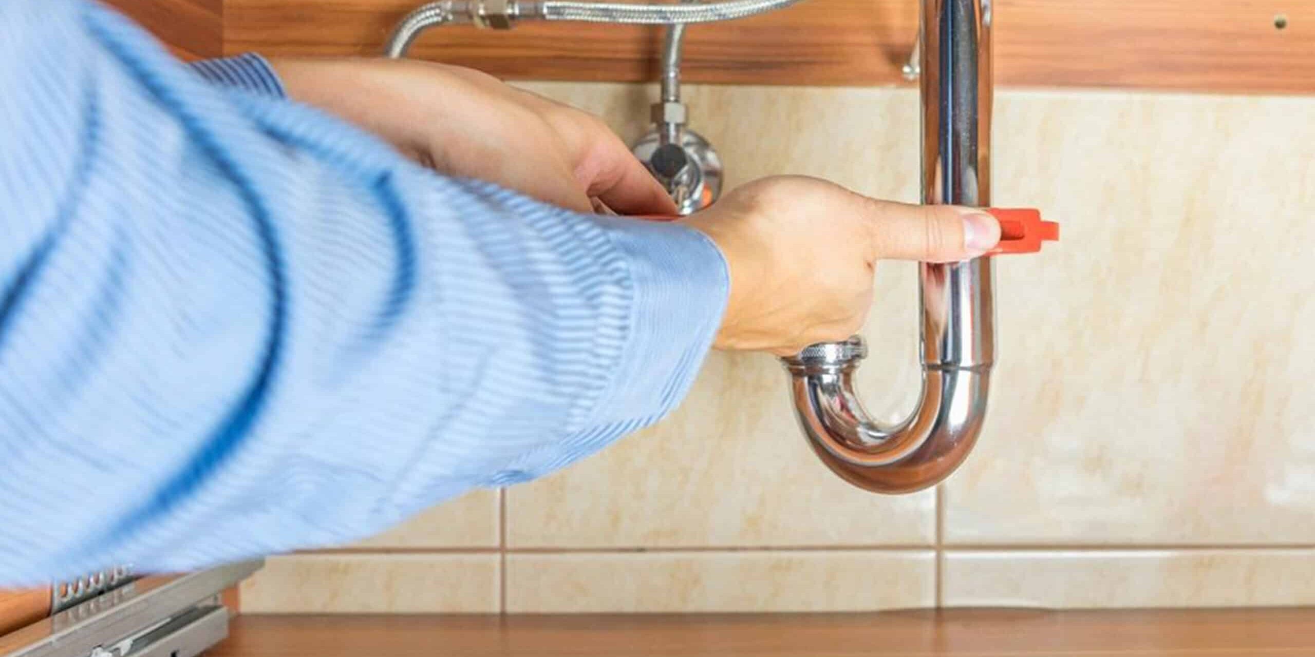 Leaking pipe repair under the sink showing professional plumbing service for leak fixing and pipe maintenance.