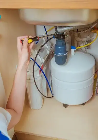 Corwell Plumbing technician repairing under-sink plumbing with tools and pipeline, emphasizing expert plumbing services and pipe repair.