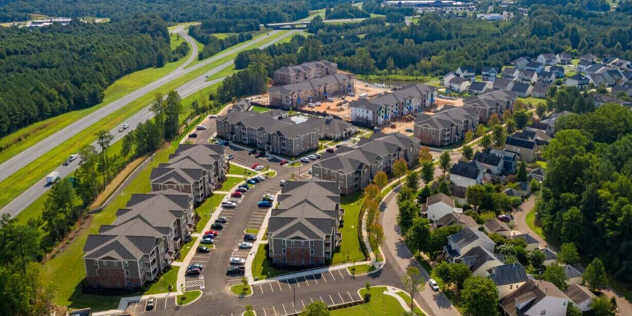 Aerial view of a residential apartment complex and neighborhood surrounded by lush greenery, highlighting professional plumbing and construction services by Cornwell Plumbing.