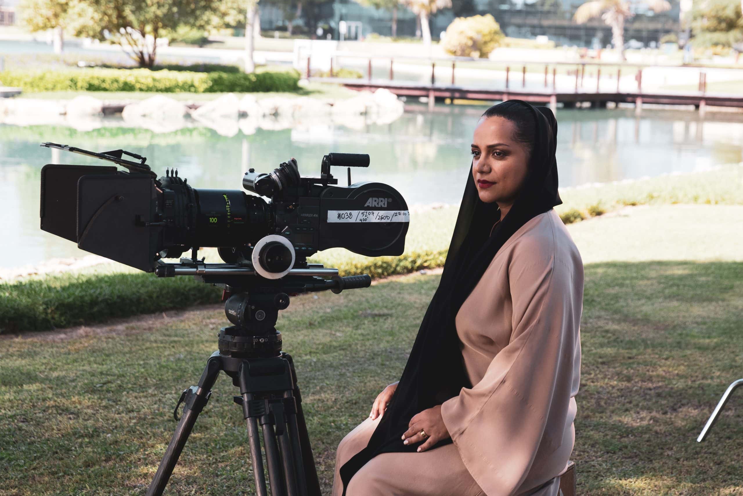 Nayla Al Khaja seated beside a film camera on an outdoor film set