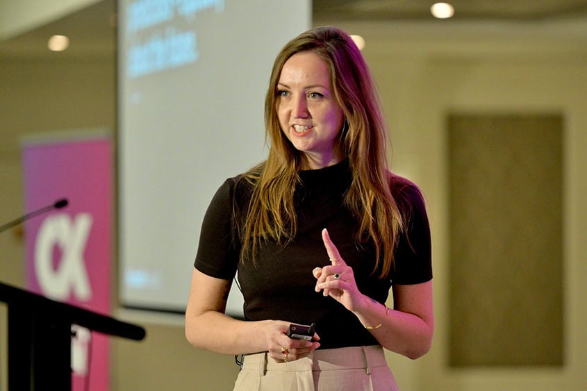 Jo Lepore speaking on stage at a CX event