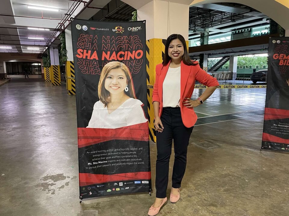 Sha Nacino standing beside her TEDx event banner