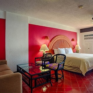 A hotel room featuring red walls and a neatly made bed, creating a warm and inviting atmosphere.