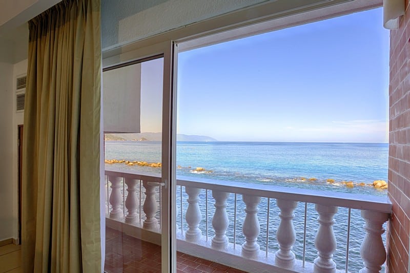 A room featuring a balcony with a stunning view of the ocean waves and horizon.
