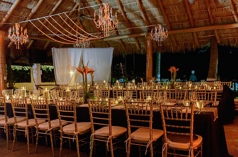 A beautifully arranged wedding reception in a lush tropical setting, featuring elegant tables and vibrant floral decorations.