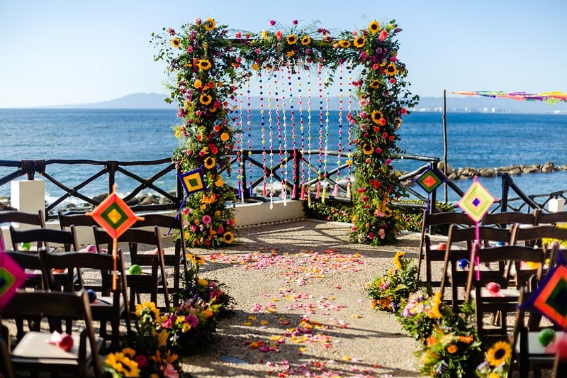 A beach wedding ceremony adorned with vibrant flowers and elegant decorations, set against a serene ocean backdrop.