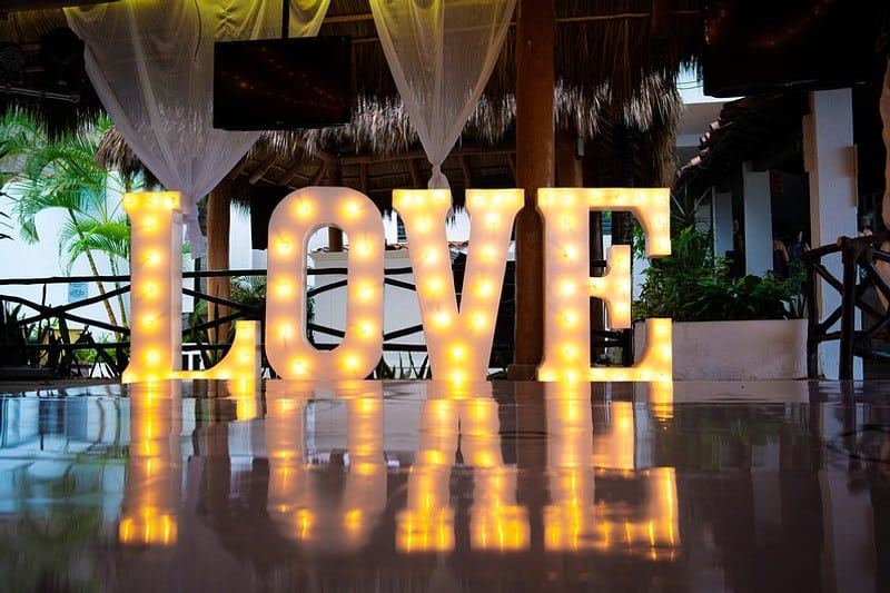 The word "love" is lit up with lights on the ground, set against a plain white backdrop.
