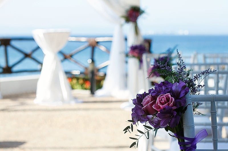 A wedding ceremony scene featuring a couple exchanging vows under an arch adorned with flowers.