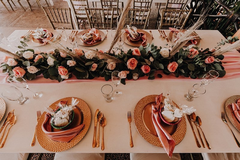 A beautifully arranged table featuring pink and gold flowers with elegant gold place settings.